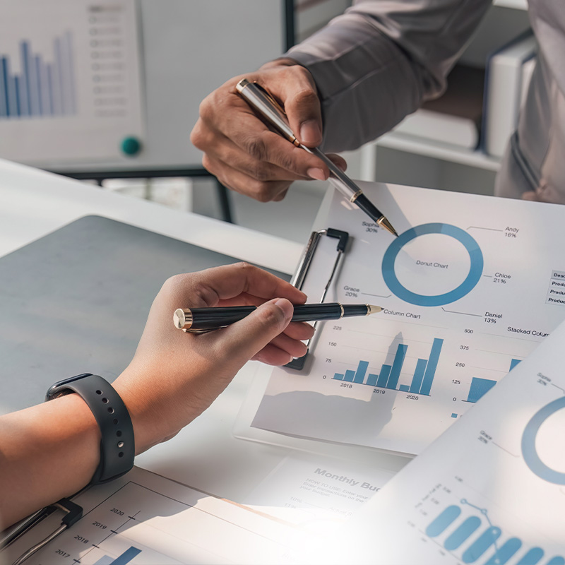 Zwei Personen besprechen Daten auf einem Dokument mit Diagrammen und Statistiken.