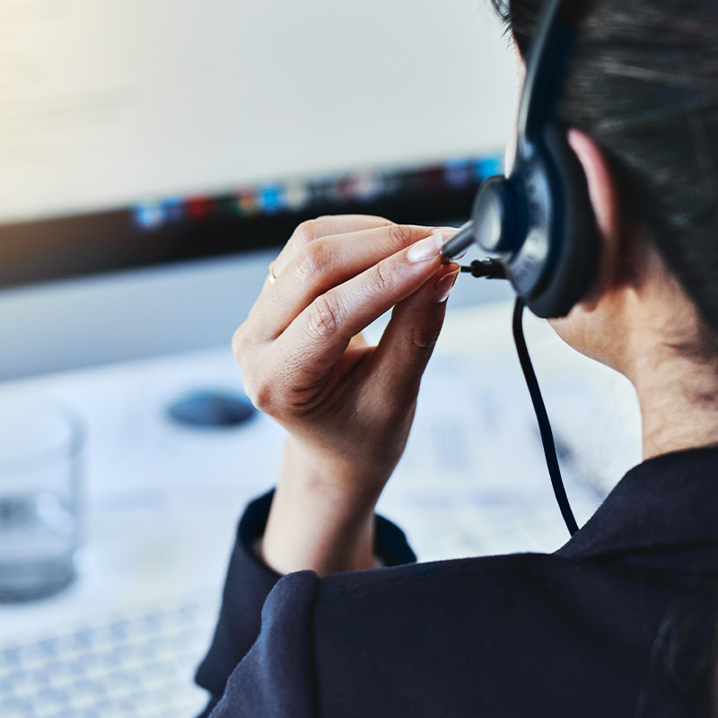 Frau mit Headset arbeitet am Computer in einem Büro.